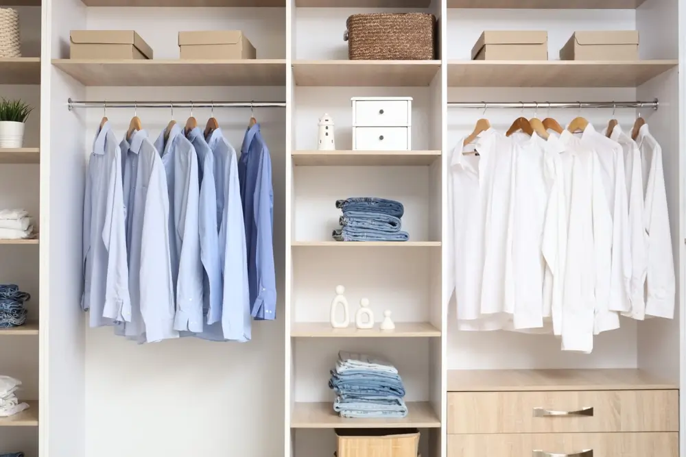 Armoire avec étagères et vêtements dans le dressing.