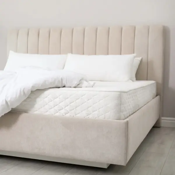 Lit confortable avec matelas doux et blanc, couverture et oreillers à l'intérieur.
